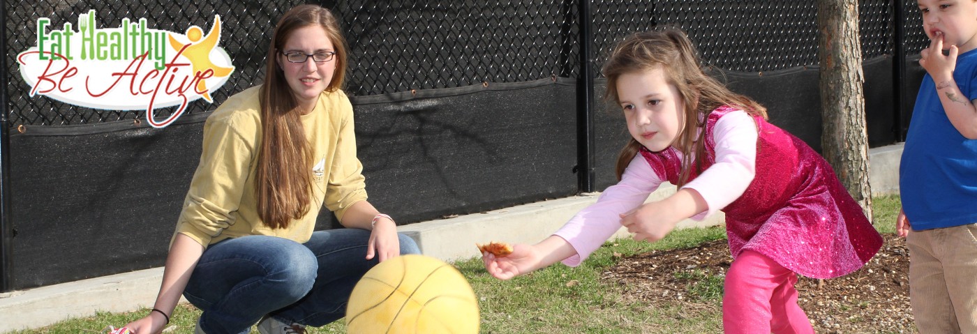 Adult with children playing with ball. Text: Eat healthy be active