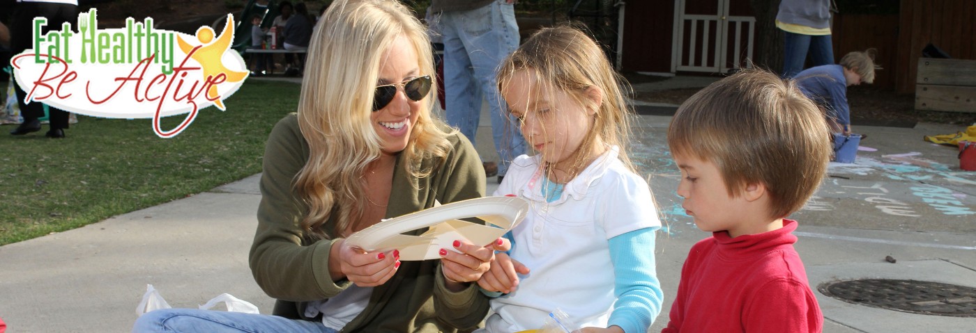 Adult with children on playground. Text: Eat healthy, be active